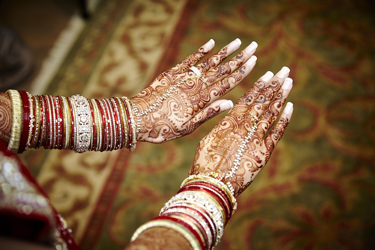 Bride's wrists stacked with red and gold bangles